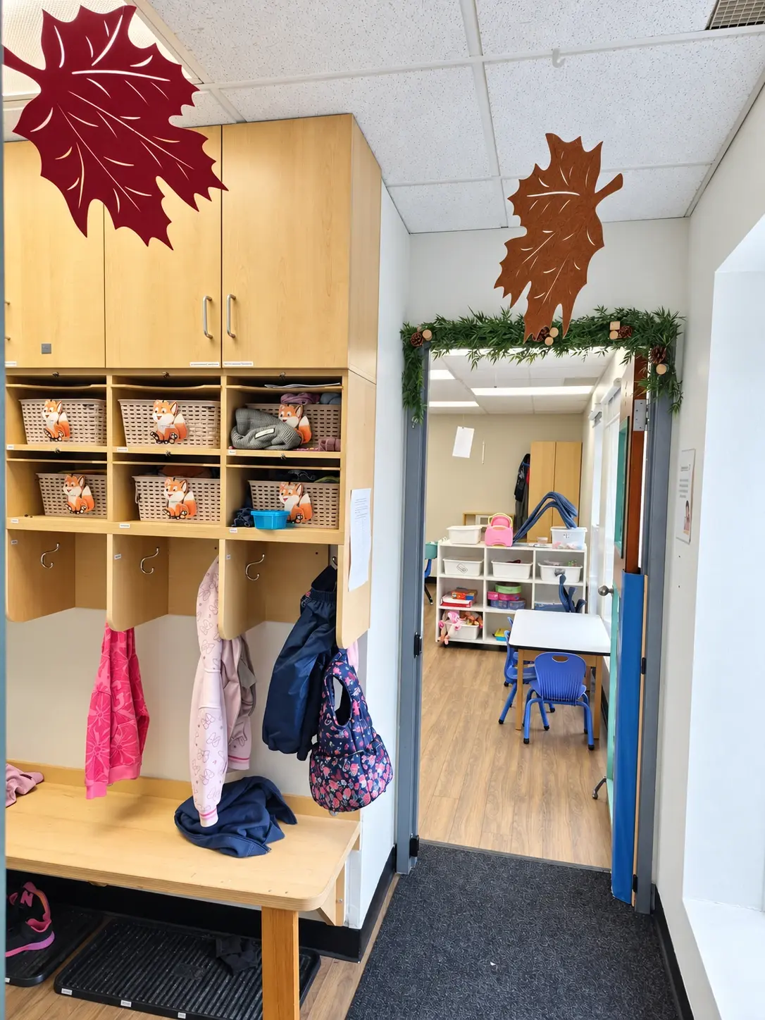 Casiers en bois avec paniers et crochets à manteaux, près de la porte d’une salle décorée de feuilles d’automne